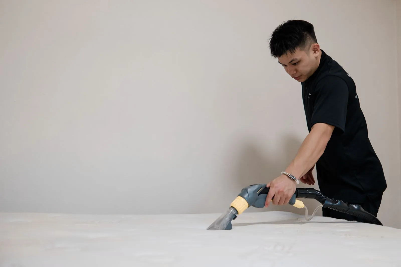 A Cleancraft technician vacuuming a white mattress with UV-C dry extraction in a Singapore home