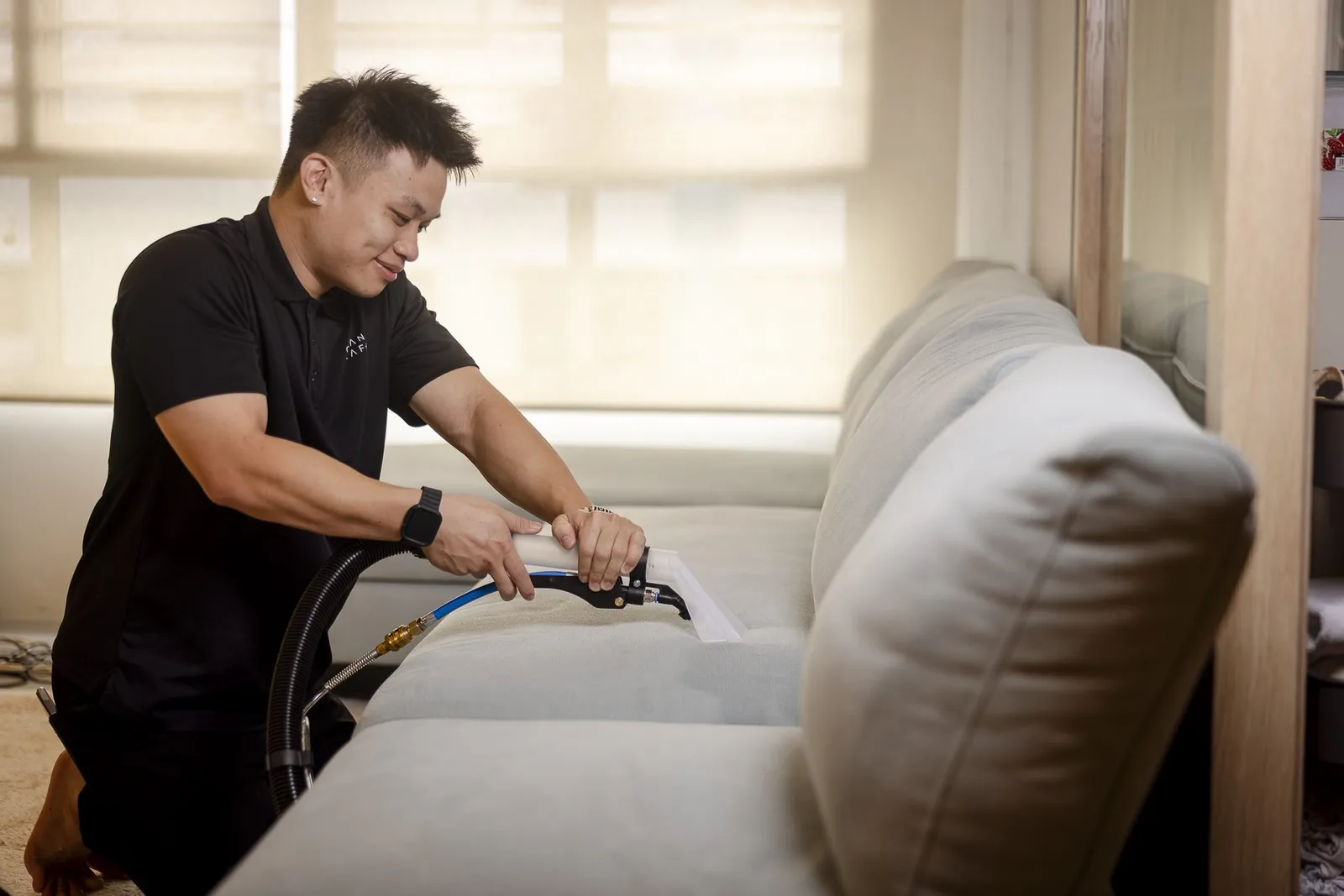 A Cleancraft technician wet-extracting a fabric sofa in a Singapore home